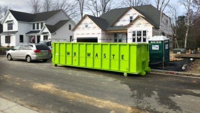 trash dumpster outside of a house in a neighborhood.