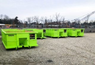 green roll off dumpsters sitting next to each other on a lot.