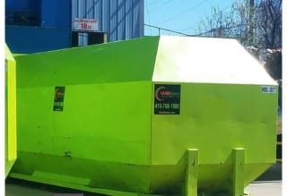 Large bright green WB Waste compactor outside