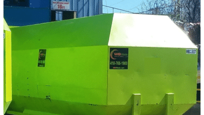Large bright green WB Waste compactor outside