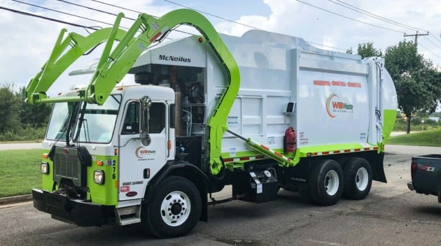 front loading garbage truck in a parking lot.