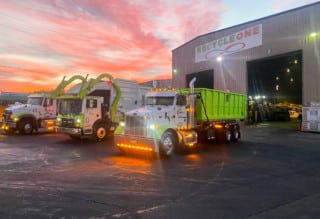 truck pulling out of garage at dusk under a sign that says recycle one.
